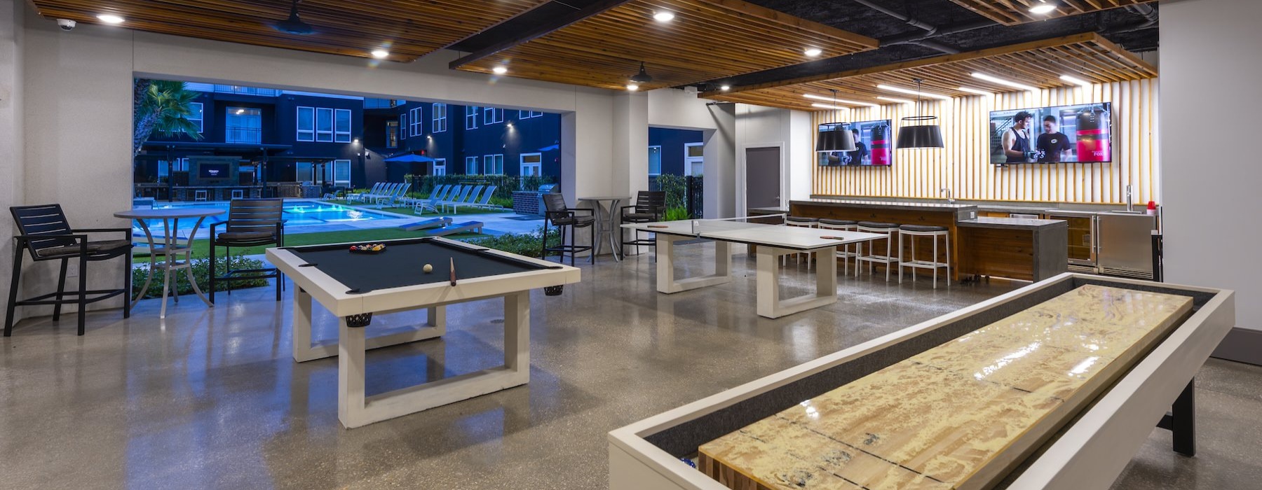 a game room with a pool table and tv's
