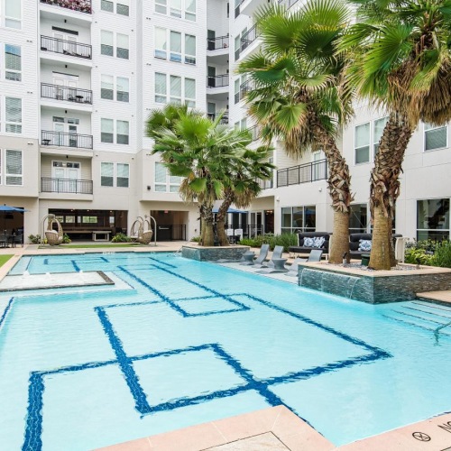 a swimming pool with chairs and palm trees